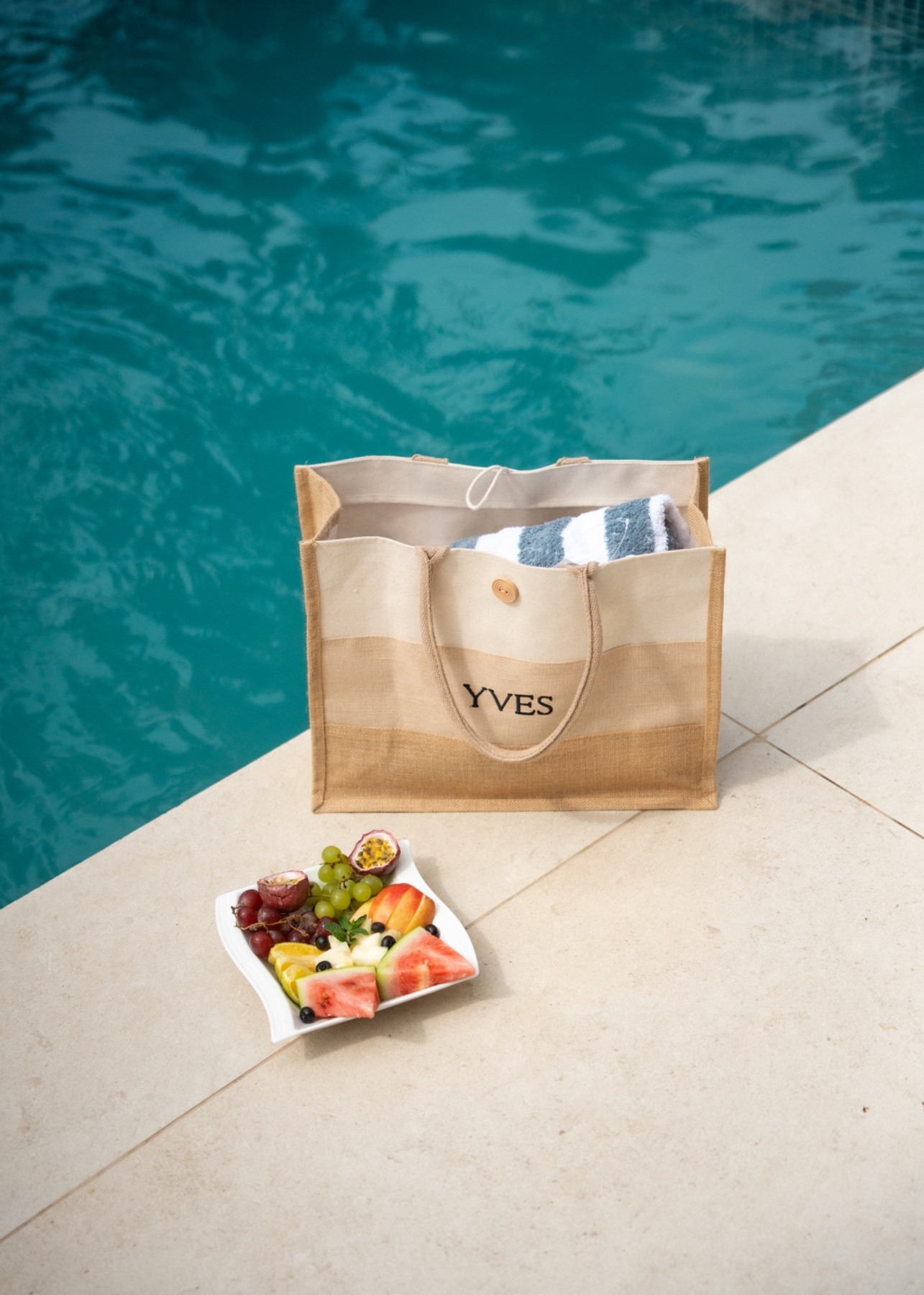Yves tote with towels and fresh fruit beside the private pool